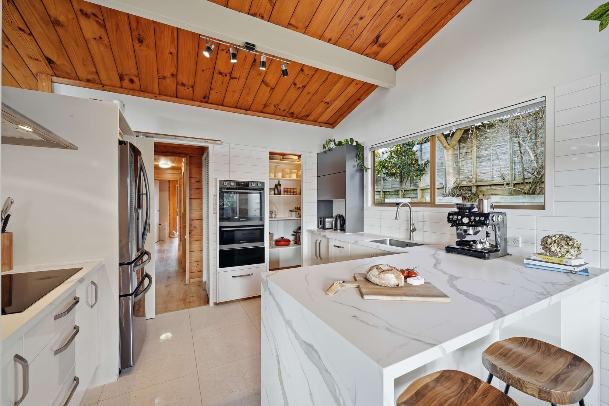 Kitchen with a marble waterfall island and timber beams