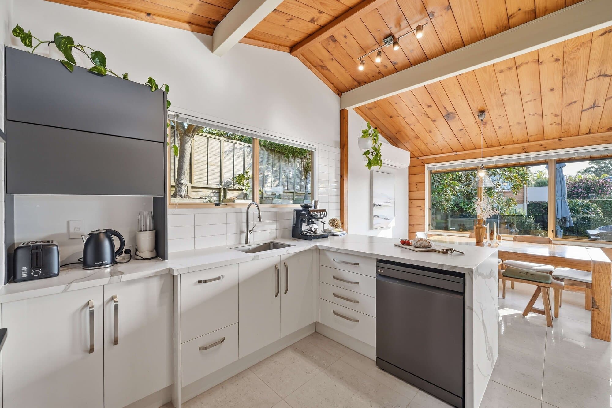 Kitchen with white cabinetry, timber ceiling, and dining beyond