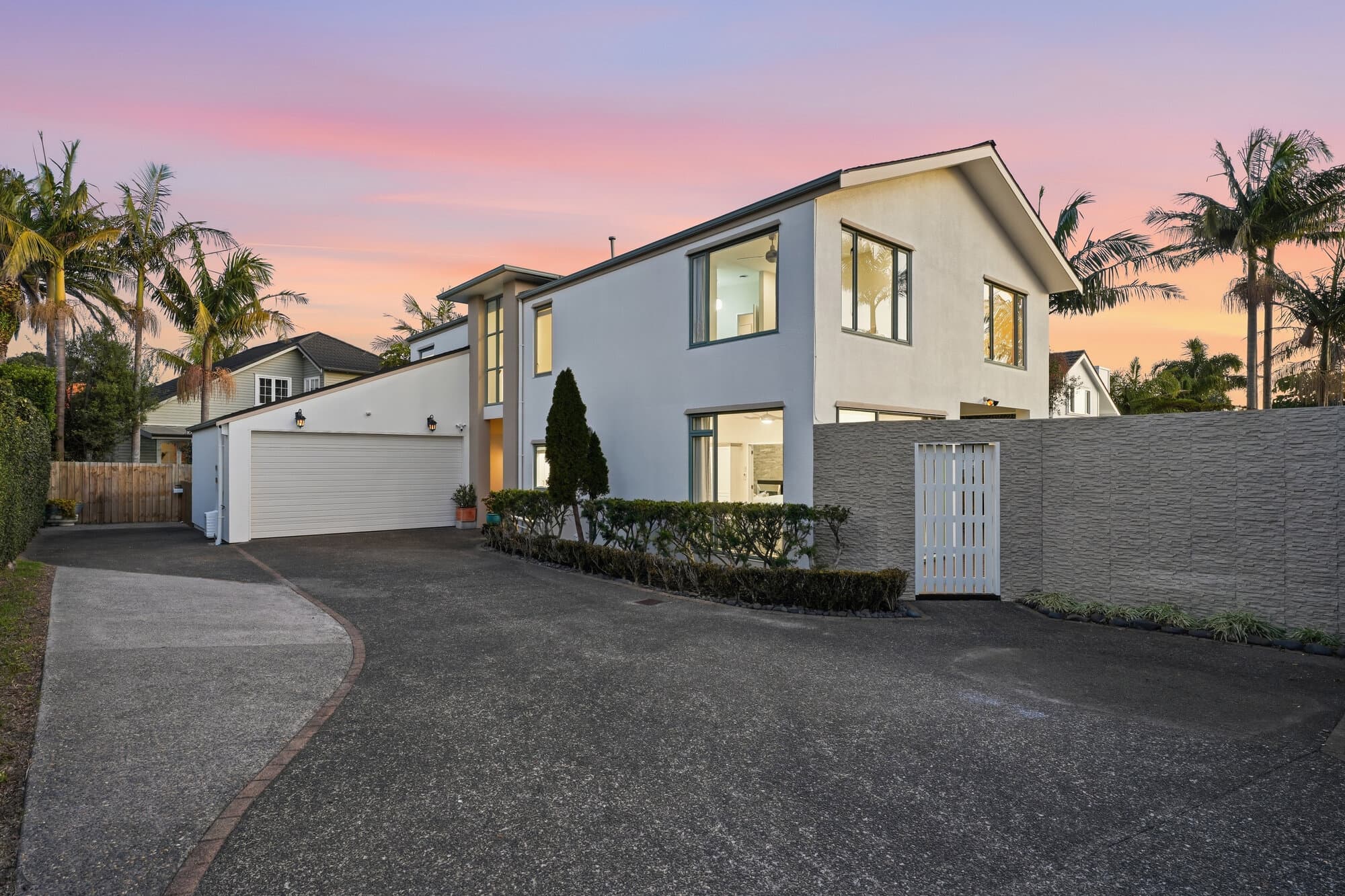 Exterior at twilight, driveway framed by palms