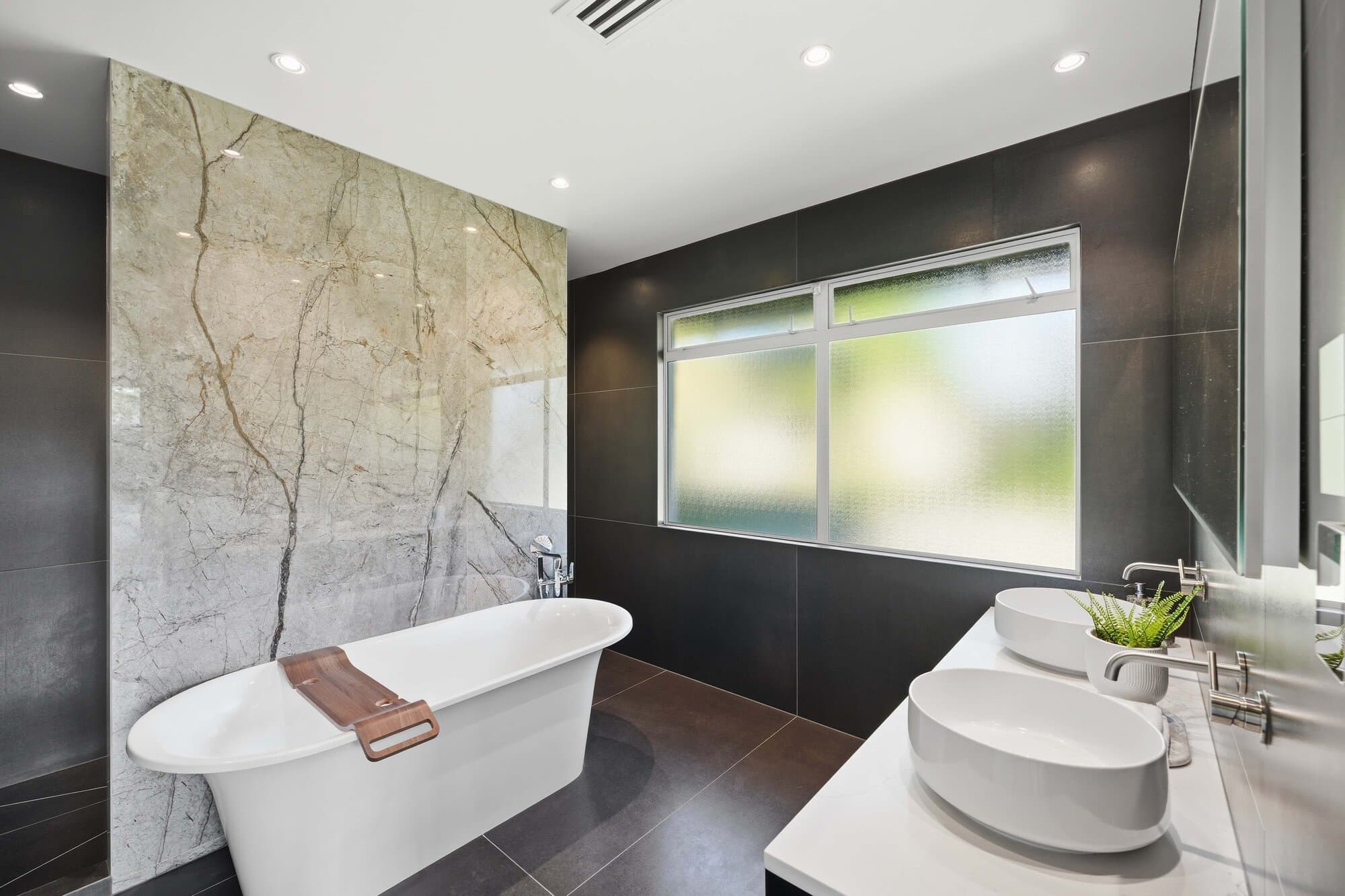 Bathroom with a freestanding tub against a natural stone wall