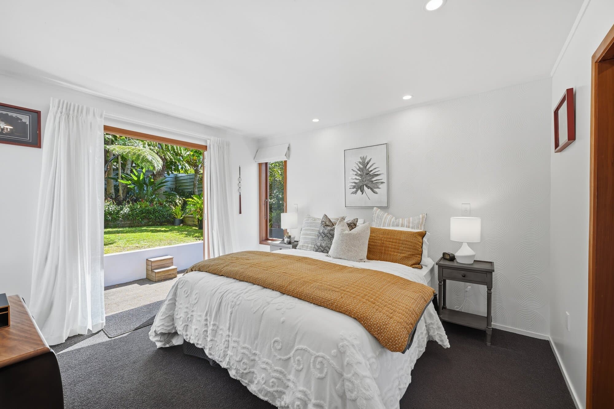 Bedroom with mustard and white bedding, timber-framed windows