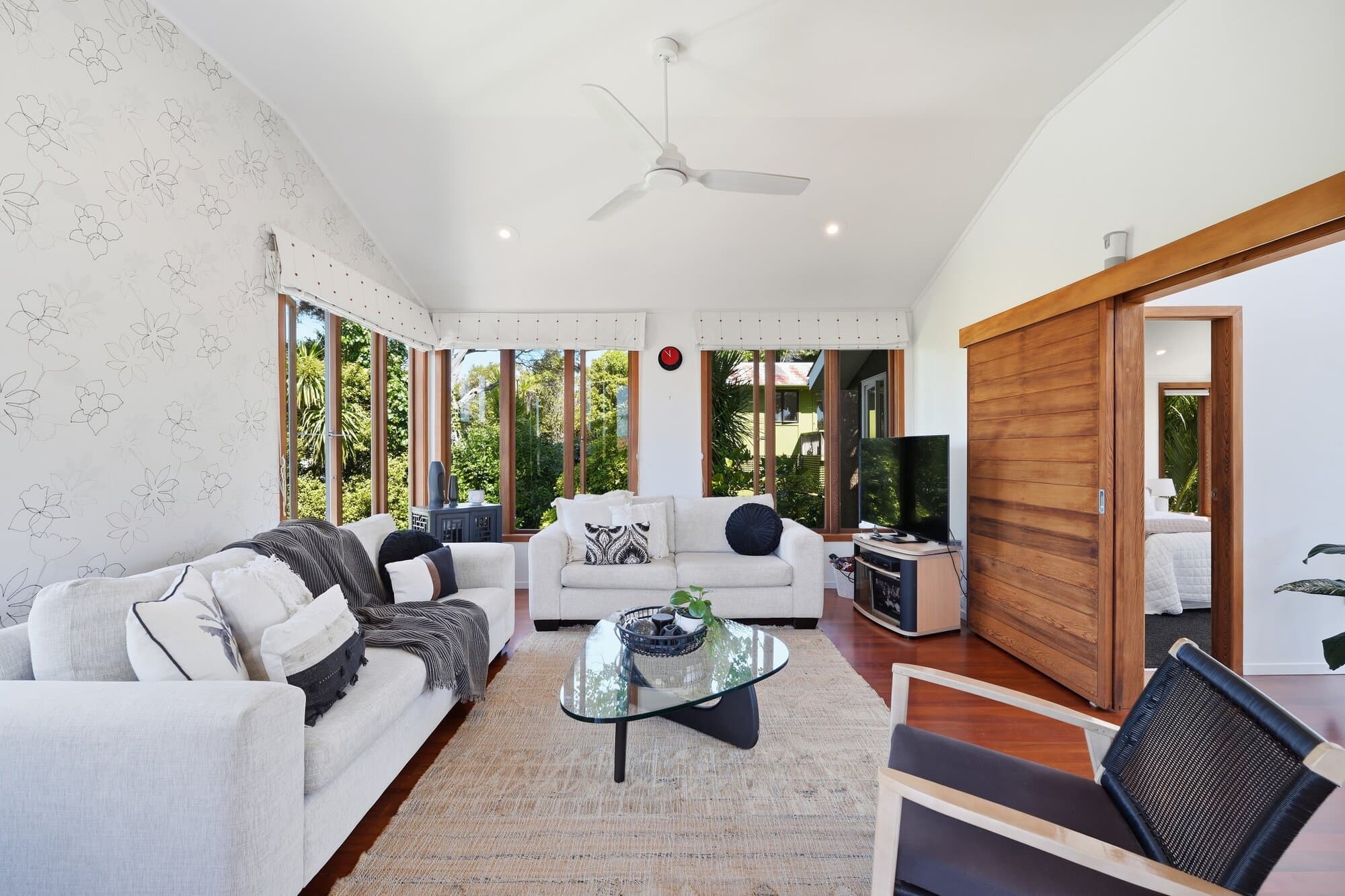 Living room with white sofas framed by garden views