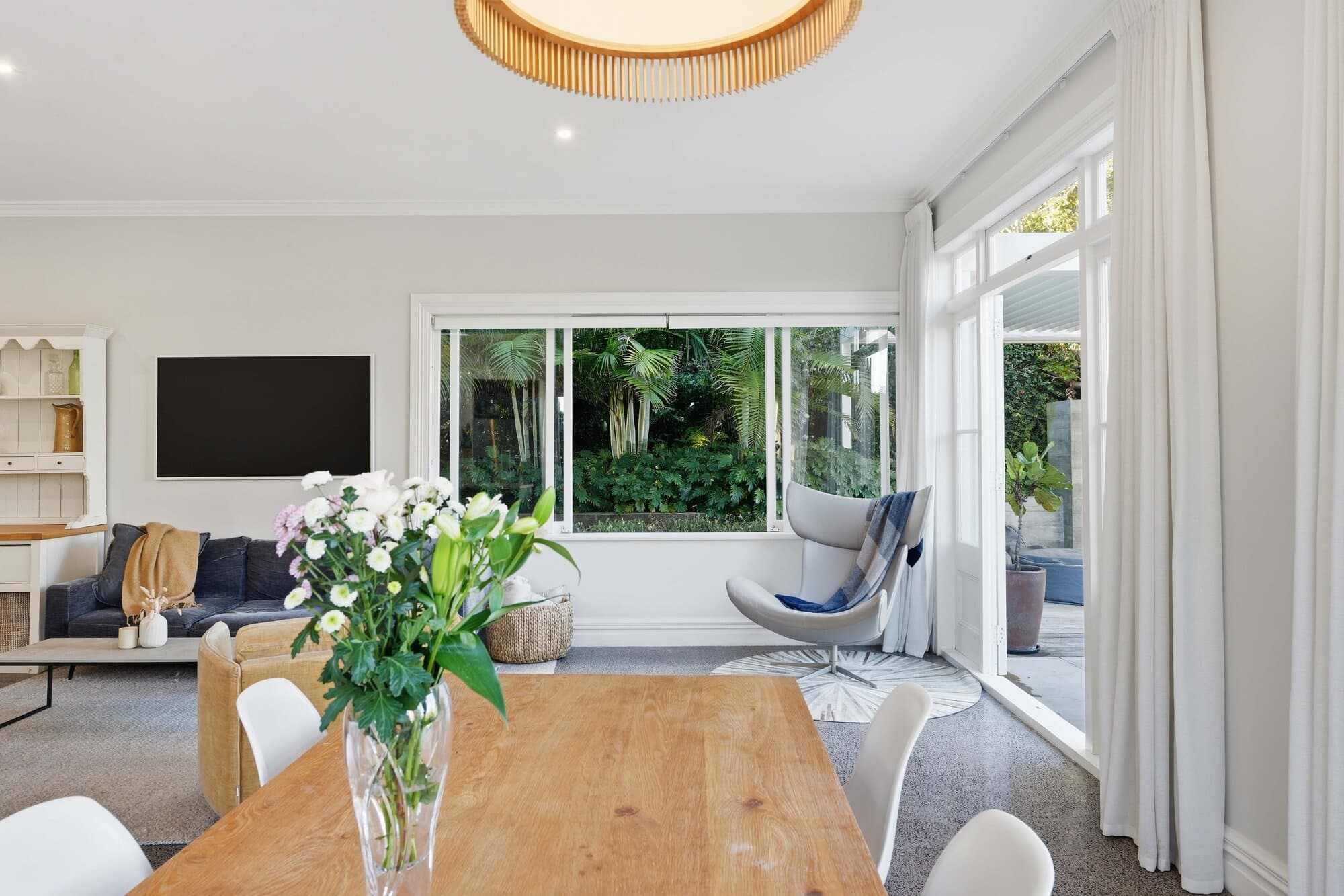 Dining area with fresh flowers and living space beyond
