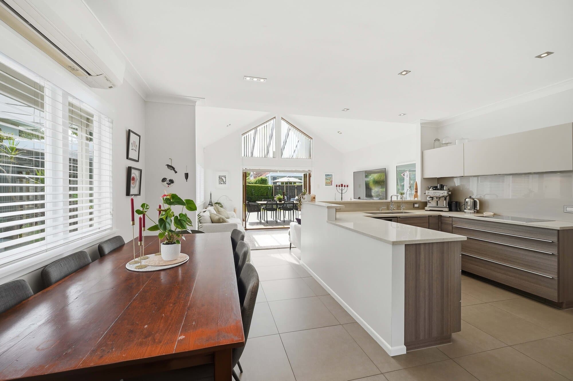 Wide angle of the kitchen and dining space beneath a vaulted ceiling