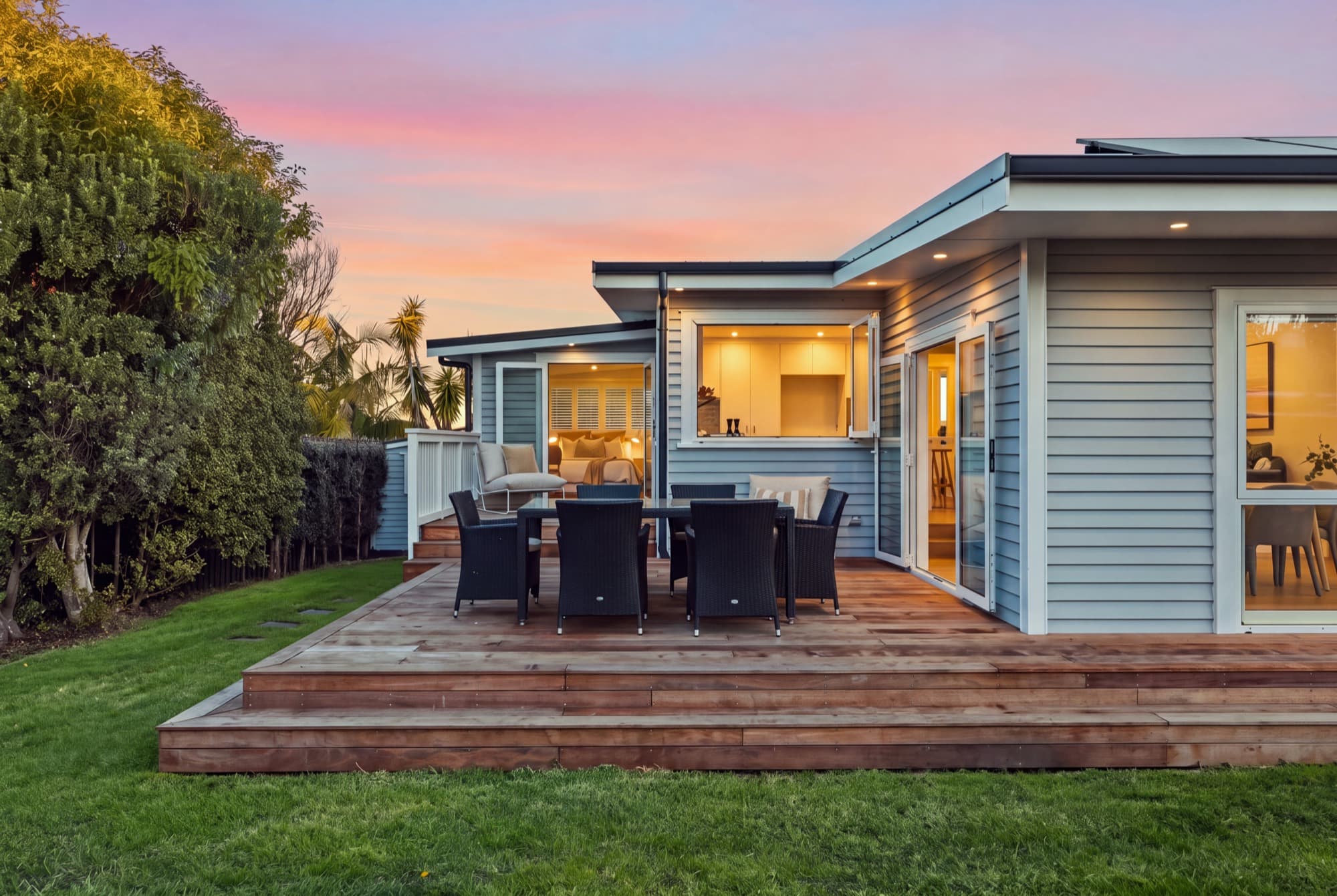 42A Old Lake Road deck and outdoor dining at twilight, the interior lit through open bifolds